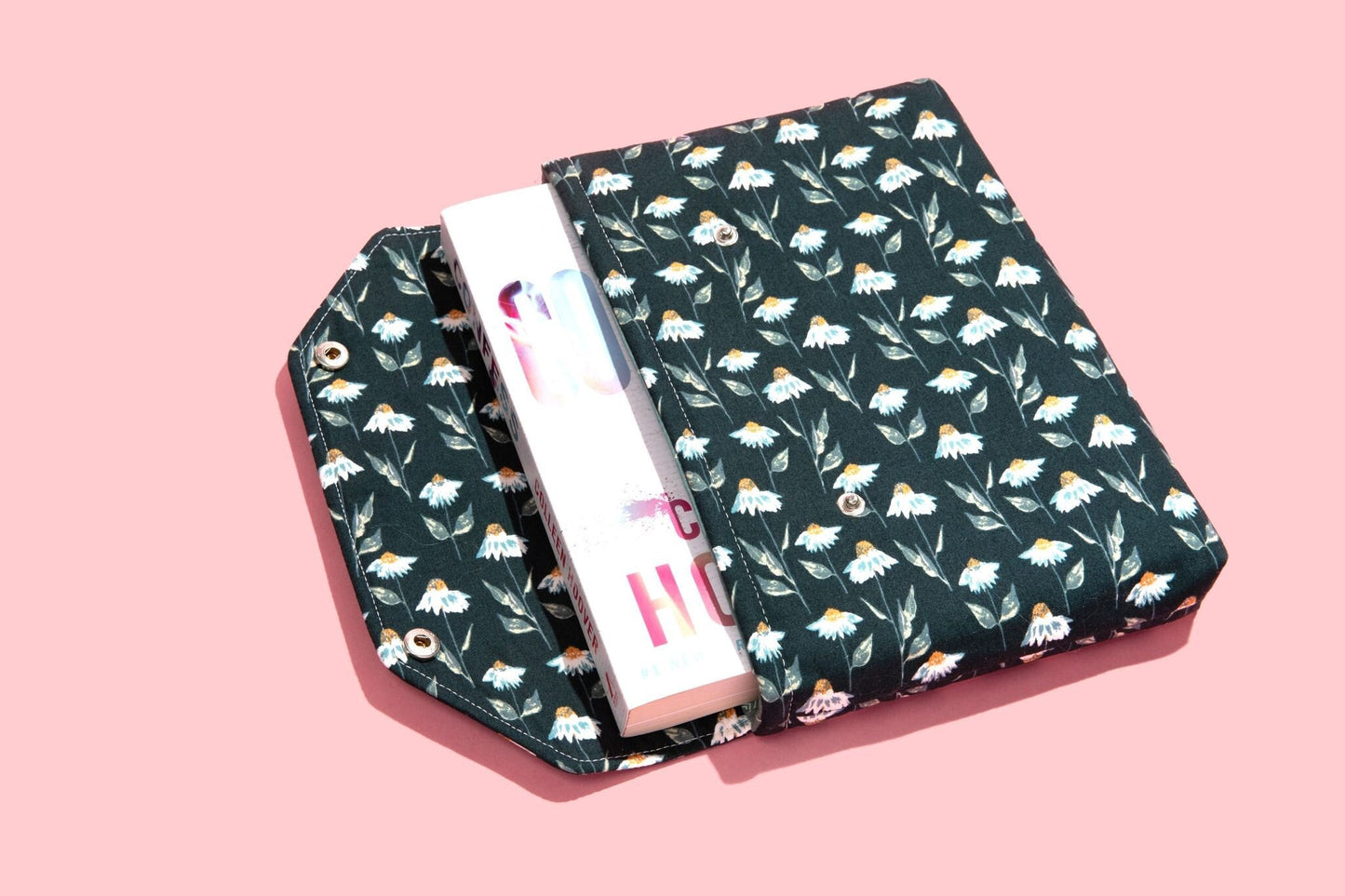 May include: A green book cover with a white daisy pattern. The cover is folded over a white book with the word &#39;HOME&#39; printed on the spine.