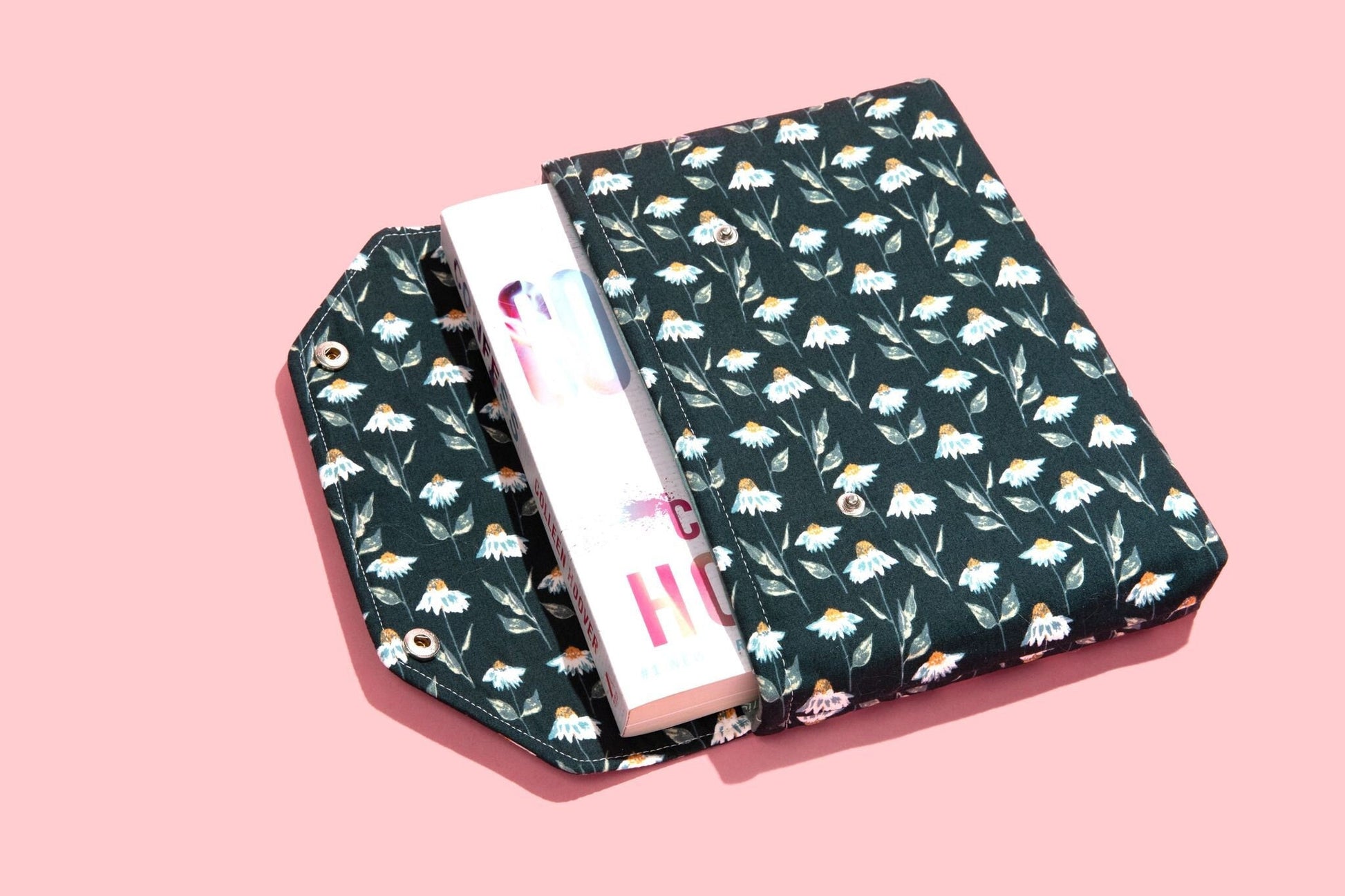 May include: A green book cover with a white daisy pattern. The cover is folded over a white book with the word &#39;HOME&#39; printed on the spine.