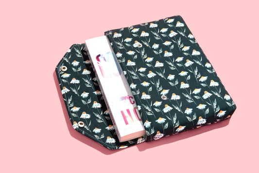 May include: A green book cover with a white daisy pattern. The cover is folded over a white book with the word &#39;HOME&#39; printed on the spine.